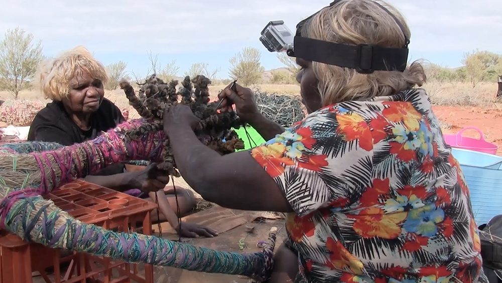 'Nora and Anawari use long sailmaker needles threaded with wool to sew in the hair. Anawari describes how they shape the hair to look like it is flying in the wind.'